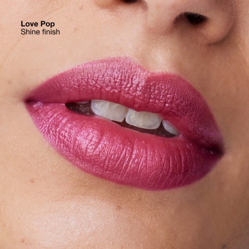 Nahaufnahme der Lippen mit pinkem Lippenstift, leicht geöffnet, zeigt Zähne, mit Text über Love Pop Lippenstift.