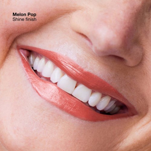 Een close-up van een lachend persoon met witte, heldere tanden en perzikhuidkleurige lippen. De tekst zegt 'Melon Pop Shine finish.'
