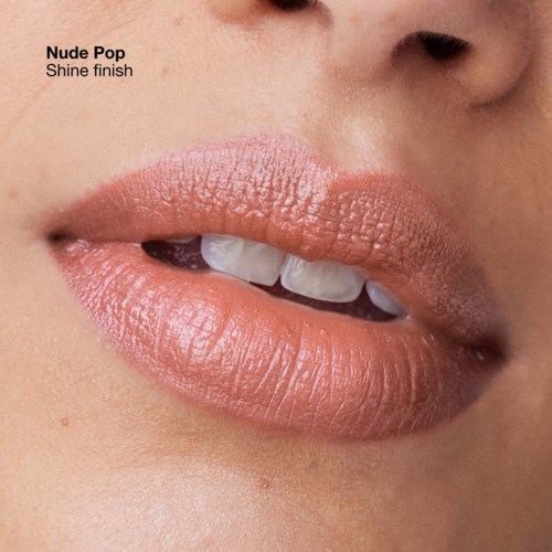 Nahaufnahme von Lippen mit weicher, glänzender Nude-Pink-Lippenstift, leicht geöffnet, zeigt Zähne, und die Haut ist glatt.