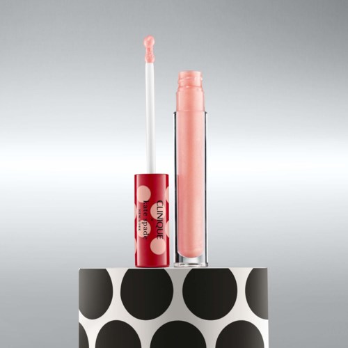 Clinique läppglansflaska med applicator, rosa färg, på en svartvit prickig ställning.