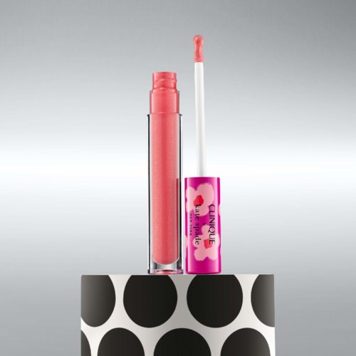 Läppglans med rosa färg och vitt appliceringsverktyg, står på en svartvit polkadot yta.