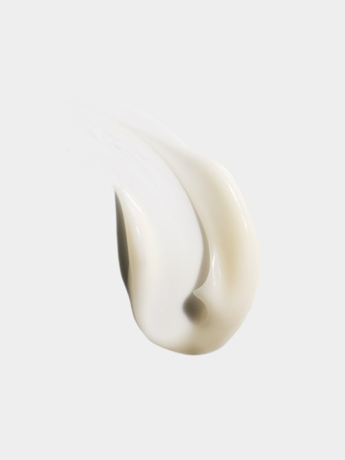 A dollop of white cream or lotion on a white surface with shadow and texture visible.