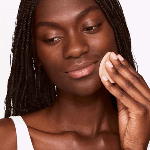 Een vrouw met gevlochten haar gebruikt een spons om make-up aan te brengen of te verwijderen.