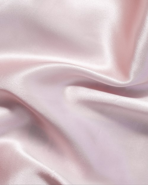 Zachte roze satijnen stof met zachte plooien en glans, lijkt glad en luxe.