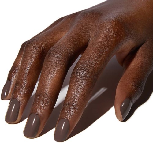 Een hand met een donkere huid en nagels die in taupekleur zijn gelakt.