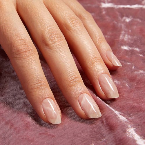 Eine Hand mit gepflegten, glänzenden, natürlichen Nägeln liegt auf einer rosa Oberfläche.
