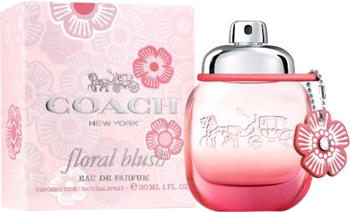 A perfume bottle with a floral design and pink and silver colors, next to a pink box with flowers and a horse-drawn carriage.