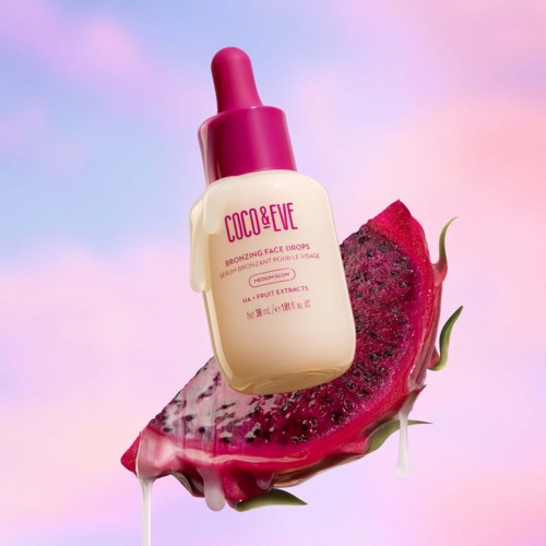 Eine Flasche Gesichts-Tropfen mit rosa Deckel, auf einer Scheibe Drachenfrucht.