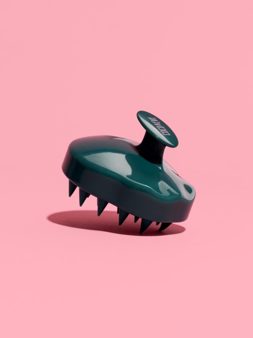 Een zwart apparaat met scherpe tanden en een ronde knop bovenop, tegen een roze achtergrond.