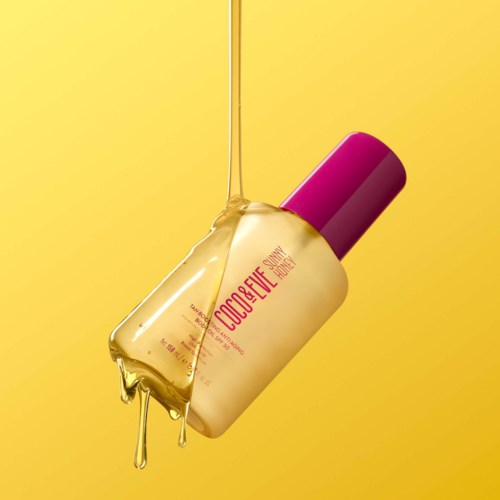 Een fles met 'Coco Beach Summer' label, gele vloeistof stroomt eruit, tegen een gele achtergrond.