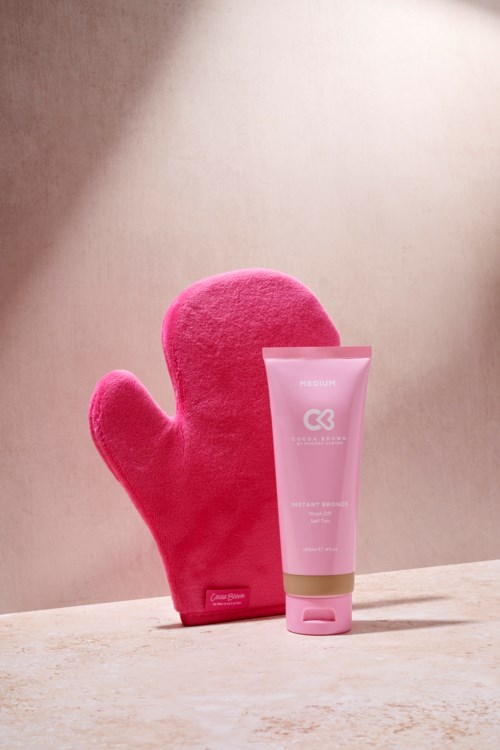 Ein pinke Plüschhandschuh und eine Tube mit pinker Hautpflegecreme auf einer hellen Oberfläche. Der Hintergrund ist schlicht und weich.