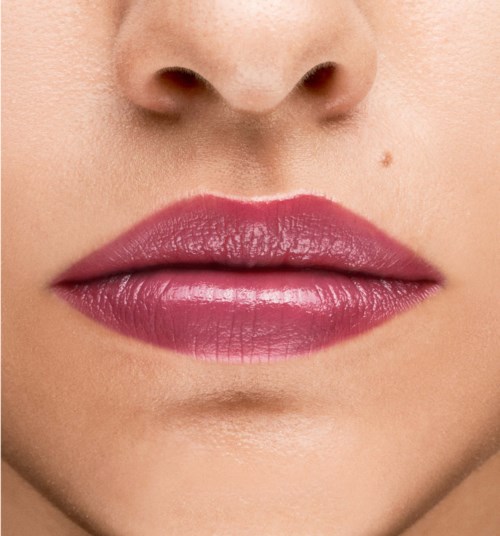 Nahaufnahme von Lippen mit rosa Lippenstift und kleiner Muttermal über der Oberlippe.
