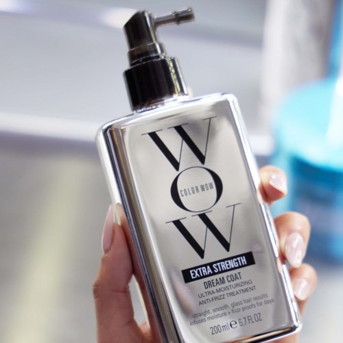 A hand holds a silver bottle labeled "WOW Extra Strength Dream Coat" with a pump dispenser.