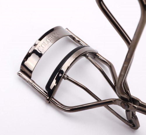 Een metalen wimperkruller met een glanzende zilveren afwerking en zwarte accenten, ontworpen om wimpers te krullen.