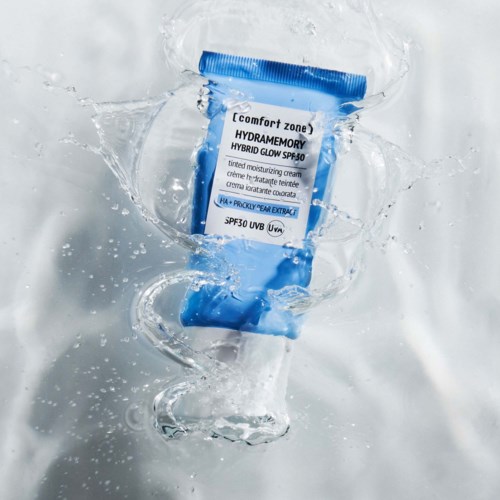 Sininen ja valkoinen putki hydramemory hybrid glow SPF50 -aurasuoja vedessä, jossa on roiskeita.