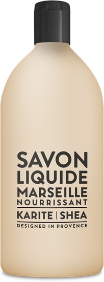 A beige bottle with black cap, labeled 'Savon Liquide Marseille Nourrissant Karité Shea, Designed in Provence.'