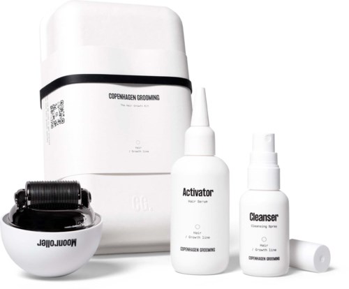 A white grooming set with bottles labeled 'Activator' and 'Cleanser', and a black roller device, for hair or skin care.