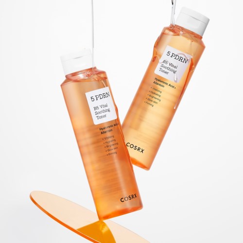 Twee oranje flessen met witte doppen, gelabeld voor hydraterende en kalmerende huidverzorging, lijken tonerflessen. Water wordt in de ene gegoten.