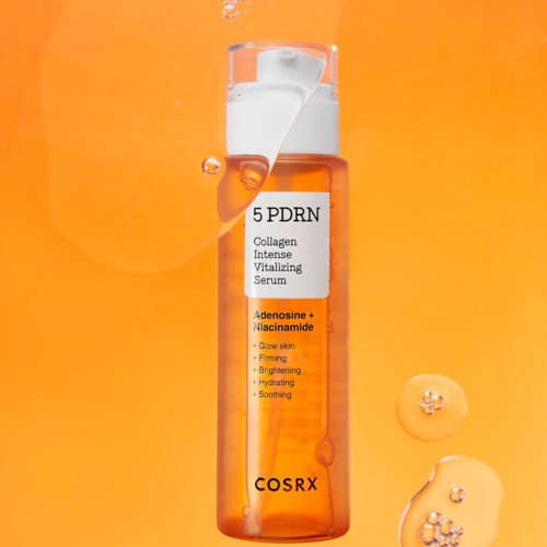 A skincare serum bottle with white label and orange liquid, floating droplets, and a yellow-orange background.