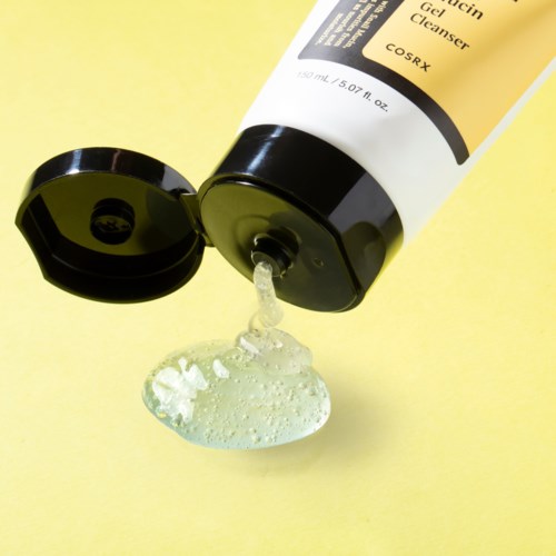 Eine gelbe Tube mit der Aufschrift 'Gesichtsreinigungsgel', aus der Gel auf gelbem Hintergrund fließt.