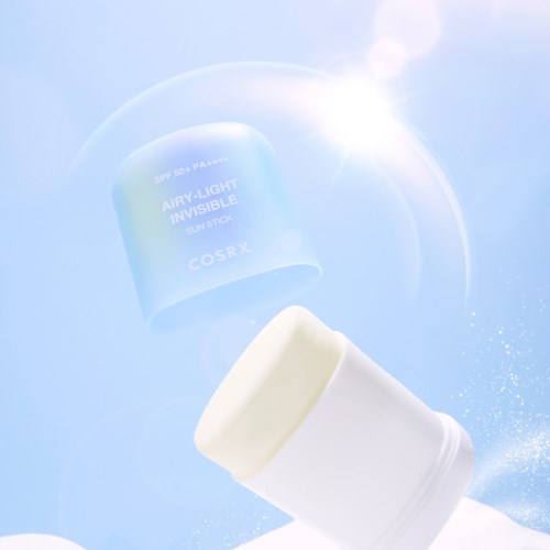 A white stick and a blue container of sunscreen fade against a bright, glowing sky with lens flare effects.