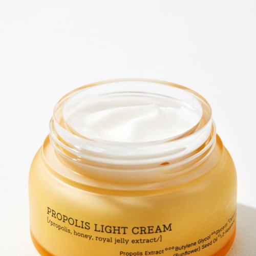 Een pot lichtgekleurde crème met label 'Propolis Light Cream' en honing en koningsgelei-extract.