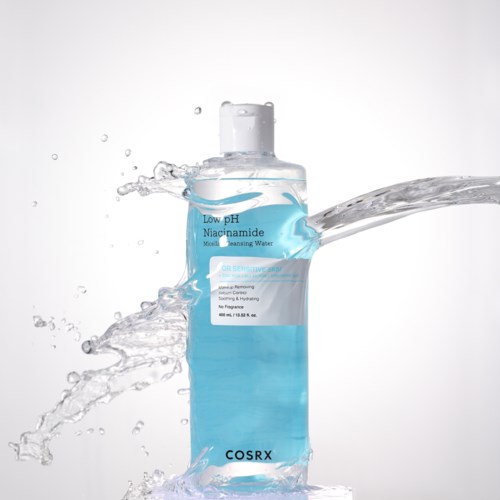 Een heldere fles met lage pH-niacinamide micelreinigingswater met spetters eromheen.