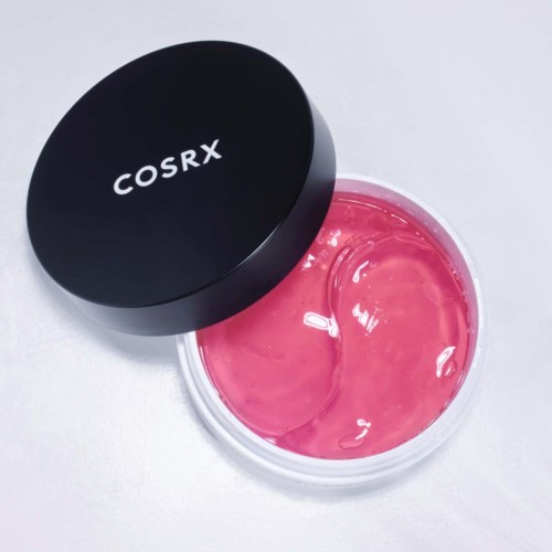 Ein runder rosa Kosmetikkbecher mit schwarzem Deckel, halb geöffnet, zeigt rosa Gel.