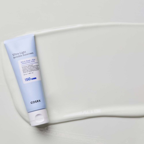 A blue and white tube of sunscreen on a white surface. The label says 'COSRX Ultra-Light Invisible Sunscreen SPF 50'.