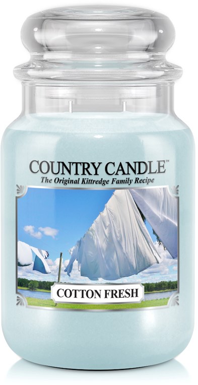 A jar of light blue scented candle labeled 'Cotton Fresh' with a outdoors scene on the label.