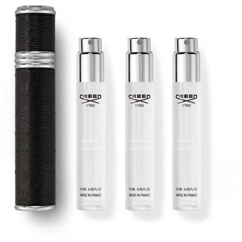 En svart og sølv beholder ved siden av tre hvite sprayflasker merket Creed Aventus. Enkel og ren oppsett.