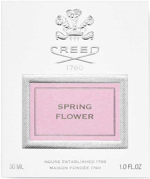 En parfymförpackning med en vapensköld, "CREED" skrivet, och rosa etikett med texten "Spring Flower".