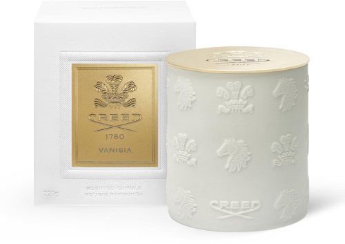 Cream-colored candle with embossed designs and a gold label featuring a crest and the brand name 'Creed'.