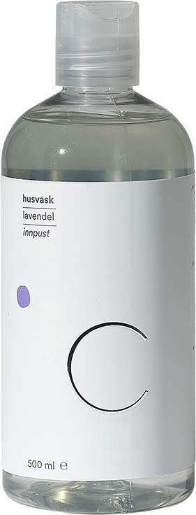 En tydlig flaska med vit etikett, lila punkt och stor svart bokstav 'C'. Den innehåller flytande tvål eller lotion.