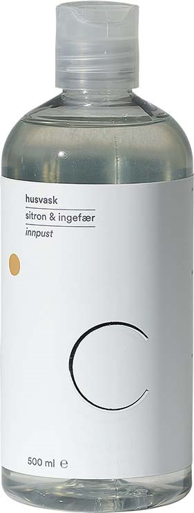 En klar flaska med vit etikett, innehållande en vätska, möjligen tvål eller rengöringsmedel, märkt på danska med citron- och ingefärslukt.