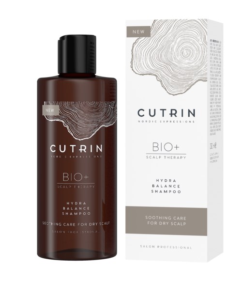 Eine braune Flasche und eine weiße Box von CUTRIN BIO+ Hydra Balance Shampoo für trockene Kopfhaut. Beides hat ein topografisches Design.