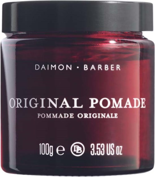 En mörkröd burk med svart lock, märkt 'Original Pomade' av Daimon Barber, innehållande 100g produkt.