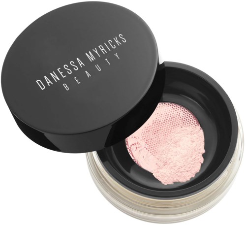 Runde schwarze Dose mit pinkem Pulver im Inneren, beschriftet 'Danessa Myricks Beauty' auf dem Deckel.