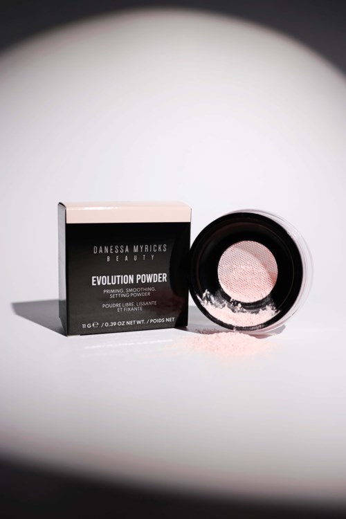 Eine schwarz-weiße Schachtel mit der Aufschrift 'Evolution Powder' neben einem runden Behälter mit rosa Pulver.