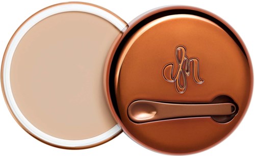 A round compact with beige face powder inside and a rose gold lid with a logo and a mirror.