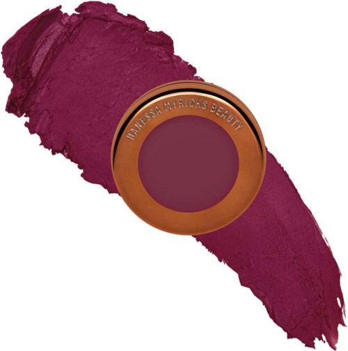 Ein runder Make-up-Produkt mit den Worten "Ultressa Byricks Beaut" darauf, auf einem Klecks dunkler pinker Lippenstift.