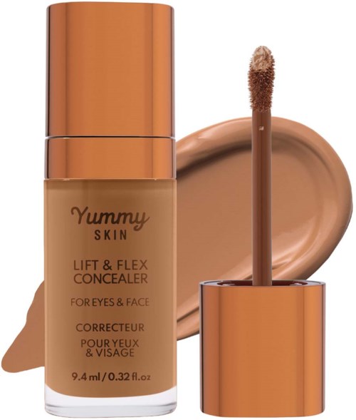 A bottle of Yummy Skin concealer with applicator, lying next to a spread of the product on a surface.