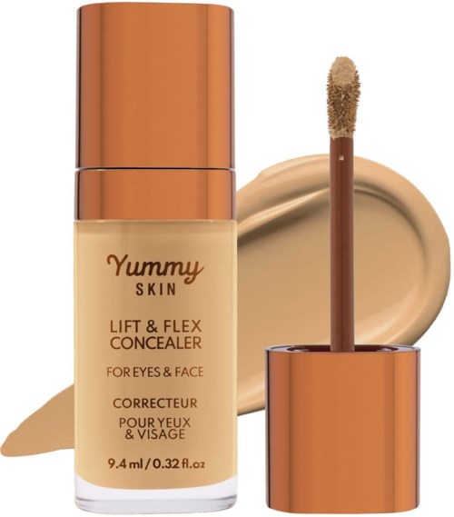 A concealer tube with a wand and a beige concealer spread on a surface. Copper-colored cap and cap insert.