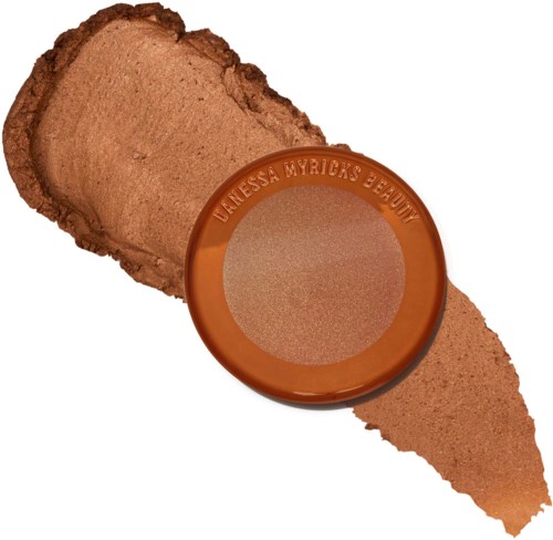 Ett brunt pressat puder i en rund behållare märkt 'Denessa Merrick's Beauty', med lite utstruket på en vit bakgrund.