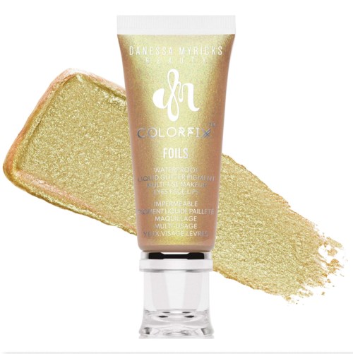 Dit is een goudkleurige make-uptube met een gouden spons of swatch erachter.