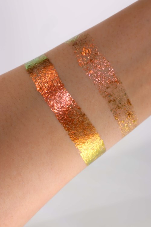 Swatches of colorful metallic eyeshadow on arm in green, orange, and gold shades with glittery finish.
