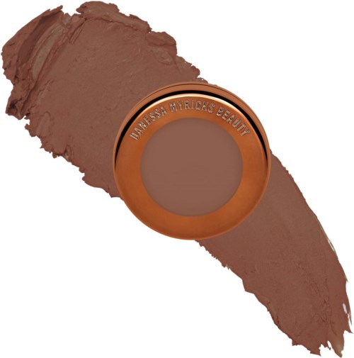 Ein kleiner, runder Make-up-Produkt mit dem Markennamen 'Manessa Wyricks Beauty', zermahlener brauner Puder darum herum.