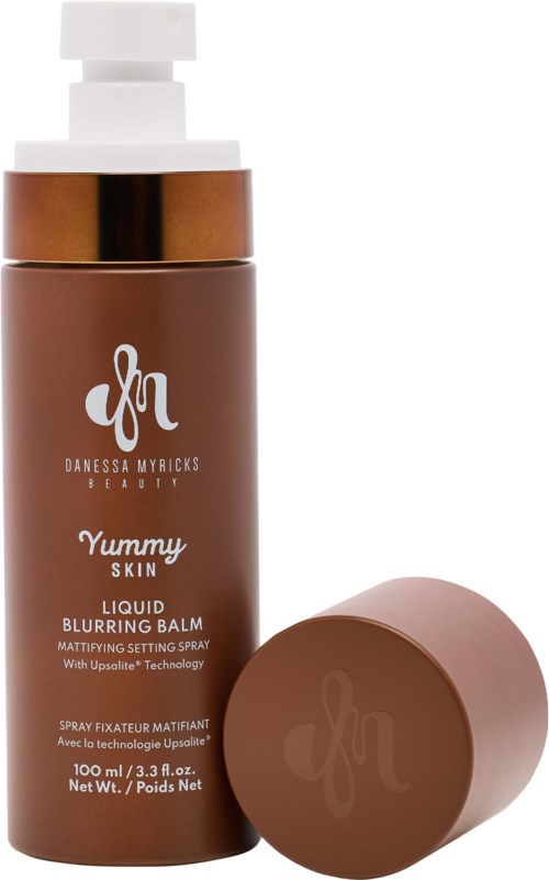 Eine braune Flasche mit weißer Pumpe, Etikett sagt "Yummy Skin Liquid Blurring Balm" und ein passender Deckel daneben.