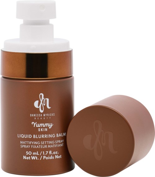 Eine braune Flasche mit weißem Pumpenverschluss und separater brauner Kappe, beschriftet 'Yummy Skin' flüssiger Unschärfebalsam.