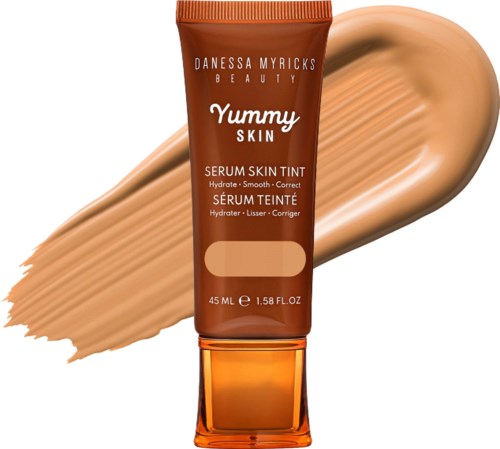 A tube of serum skin tint from Danessa Myricks Beauty, with a swatch of beige-colored product behind it.